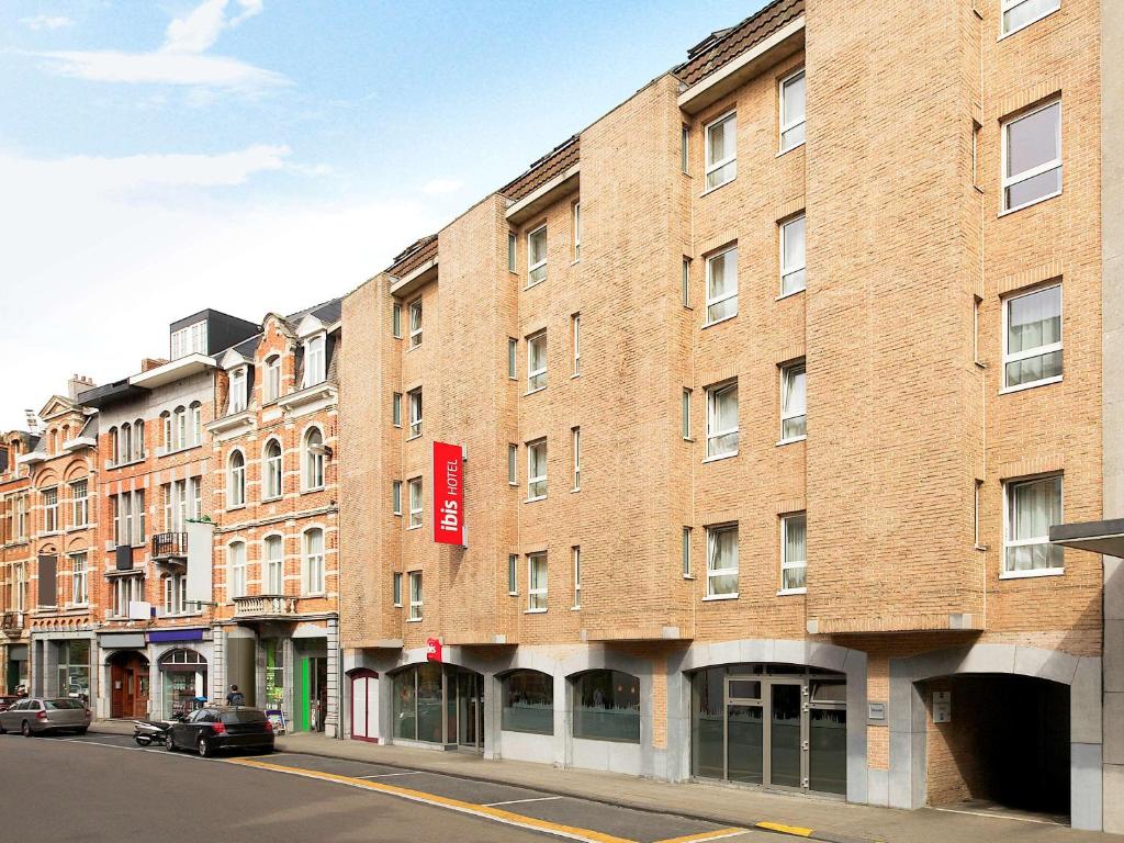 un grand bâtiment en briques sur le côté d'une rue dans l'établissement ibis Leuven Centrum, à Louvain