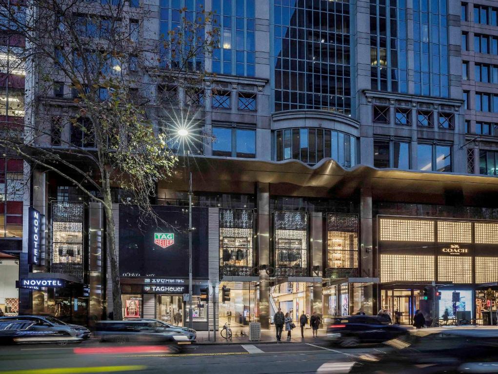 uma movimentada rua da cidade com carros em frente a um edifício em Novotel Melbourne On Collins em Melbourne