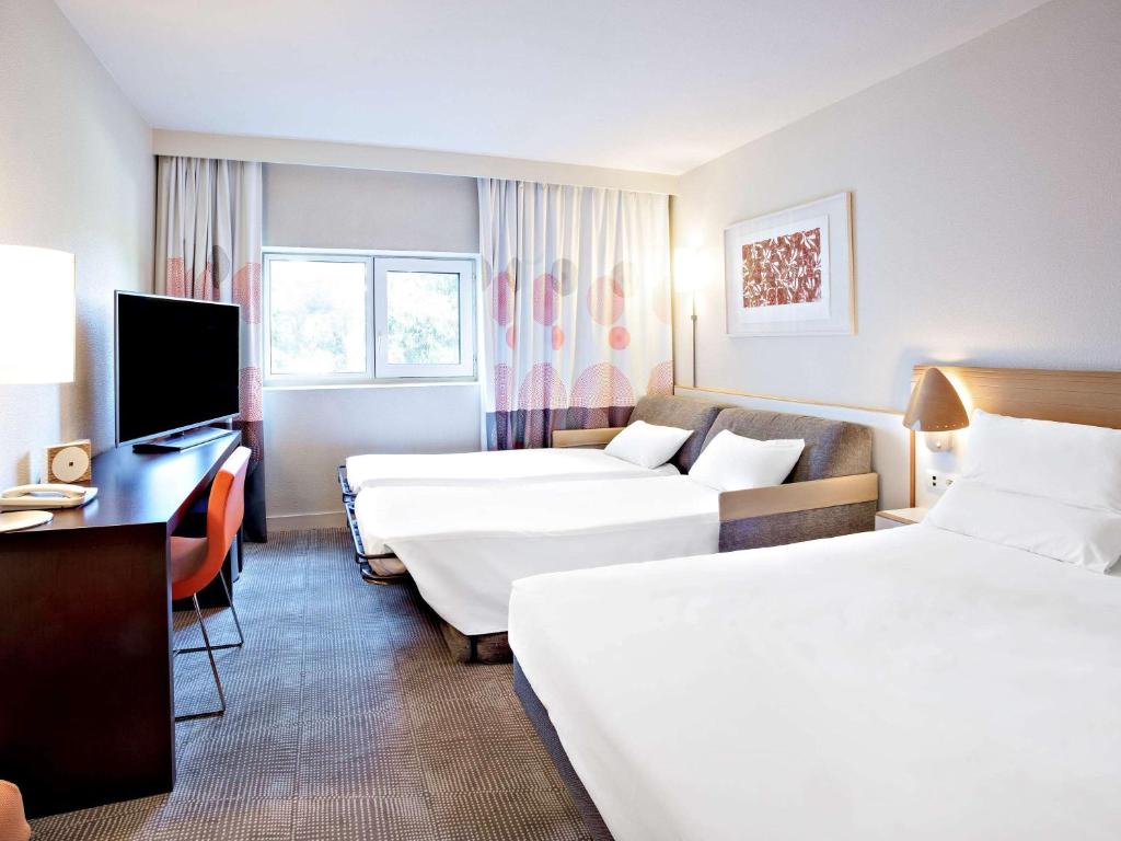 um quarto de hotel com duas camas e uma televisão em Novotel Paris Orly Rungis Aéroport em Rungis