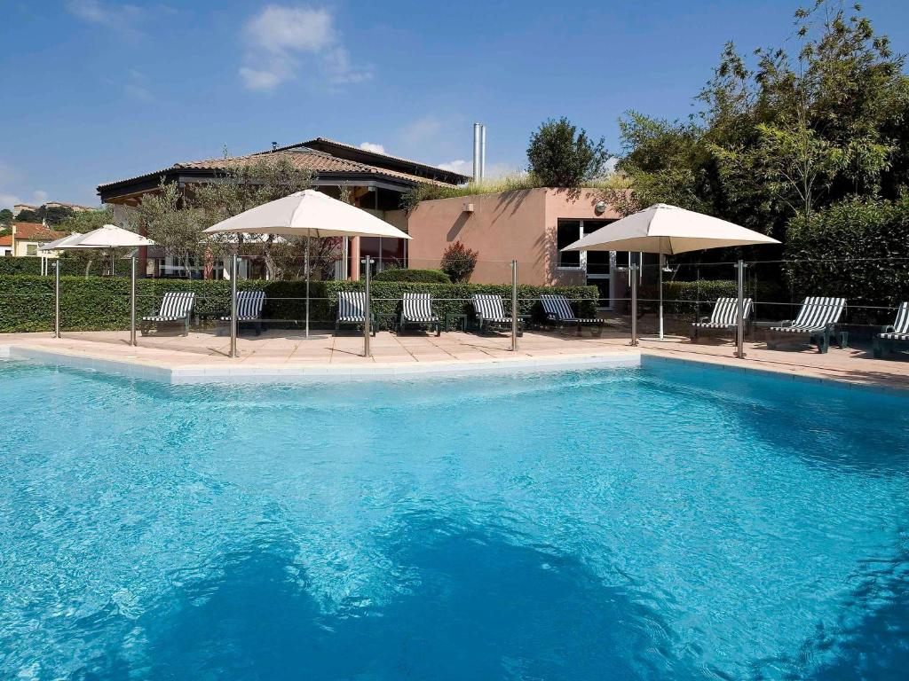 a large blue swimming pool with chairs and umbrellas at ibis Aubenas in Aubenas