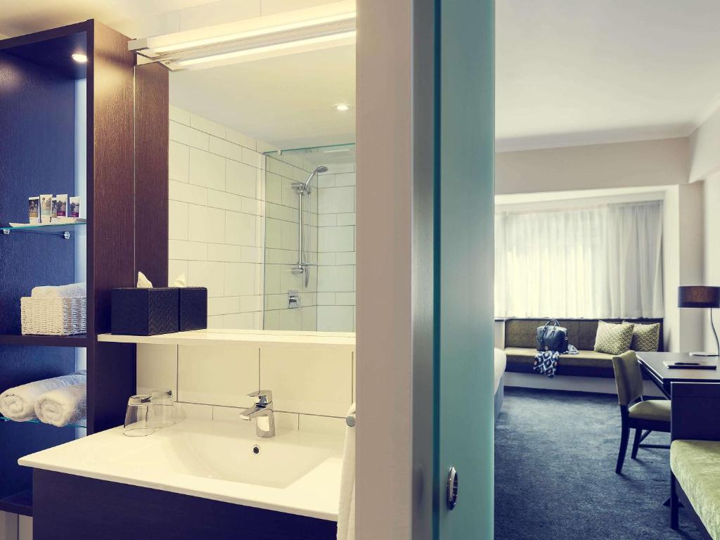 a bathroom with a sink and a shower in a room at Mövenpick Hotel Auckland in Auckland