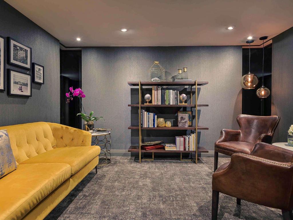 a living room with a couch and a book shelf at Mövenpick Hotel Auckland in Auckland