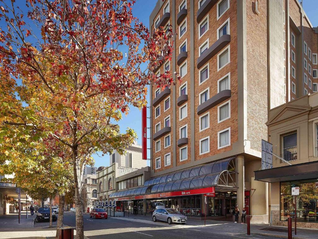 un edificio en una calle de la ciudad con un árbol en ibis Perth, en Perth