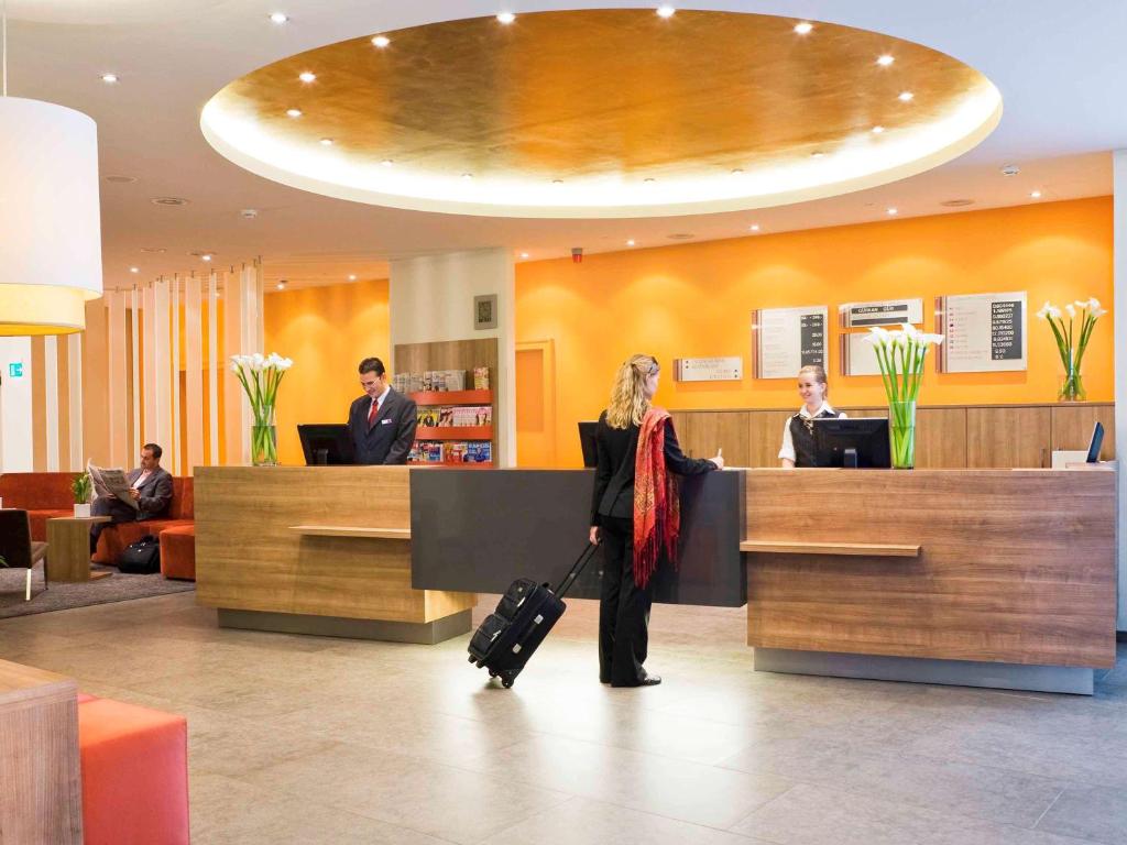 a woman standing in a lobby with her luggage at Mercure Hotel Stuttgart Airport Messe in Stuttgart
