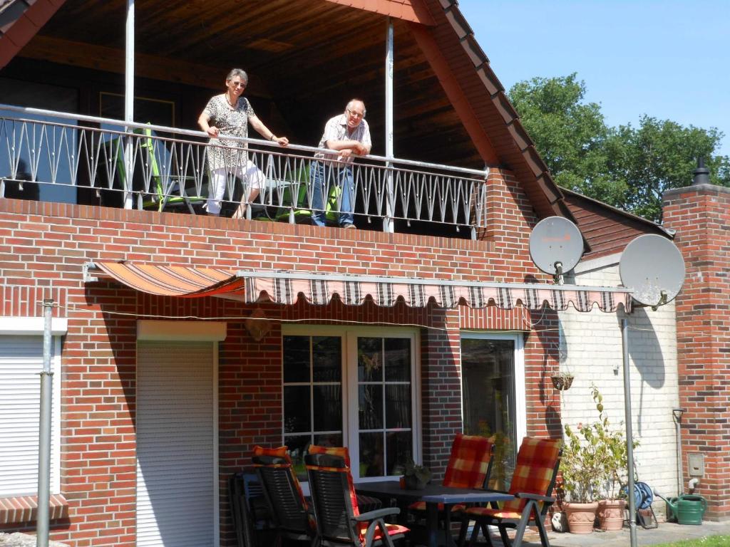 dos personas en el balcón de una casa en Ferienwohnung An der Eichenallee, 35200, en Hesel