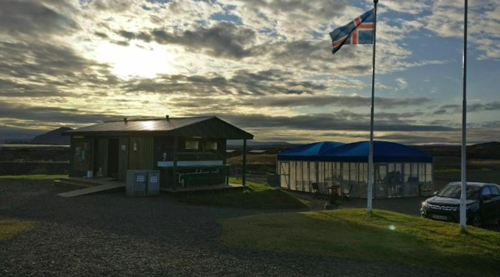 budynek z flagą i samochód zaparkowany obok niego w obiekcie Hlíd Huts w mieście Mývatn