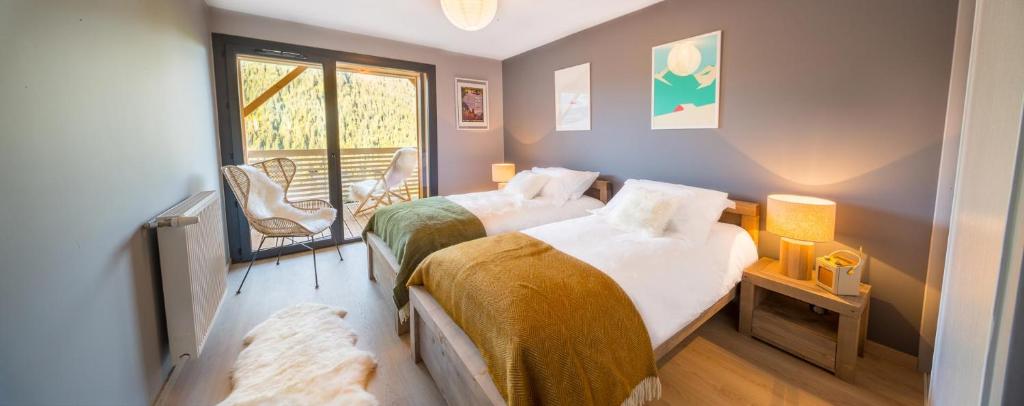 1 Schlafzimmer mit 2 Betten und einem Fenster mit einem Stuhl in der Unterkunft Les 360 - Apt 16 - BO Immobilier in Châtel