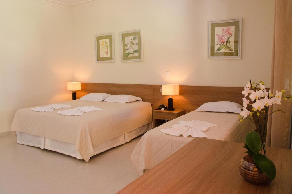 a hotel room with two beds and flowers on the floor at Villa de Holanda Parque Hotel in Holambra
