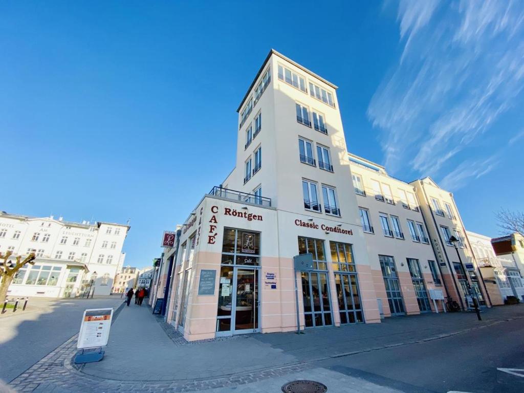 un grand bâtiment blanc dans une rue de la ville dans l'établissement Seaside, direkt an der Promenade, à Warnemünde