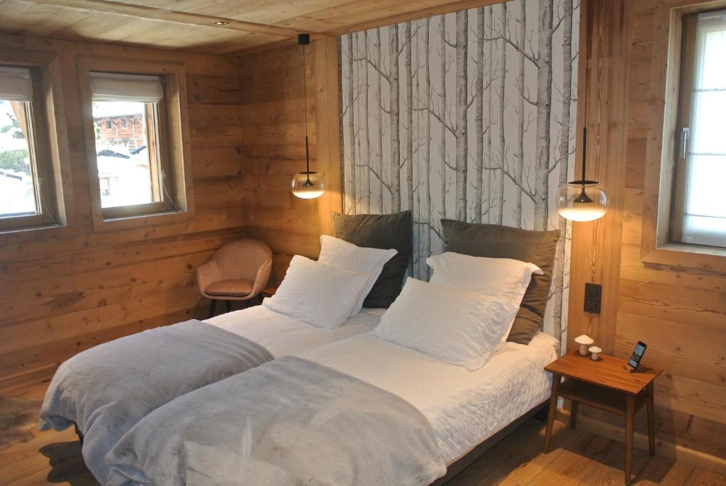 a bedroom with a large bed with white sheets and pillows at Chalet Teleporte in Les Gets