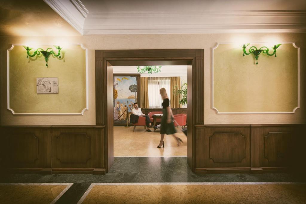 a woman walking through a hallway in a building at Artemis Hotel in Cefalù