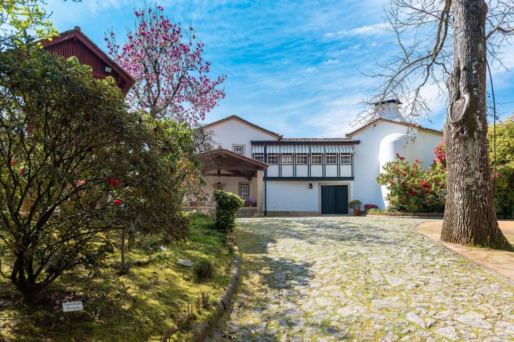 a house with a tree and a driveway at Quinta de Mourães Casa dos Rododendros in Lever