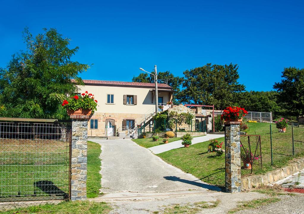 une porte menant à une maison avec des fleurs rouges dans l'établissement LE PITTURE casa di campagna, à Filiano