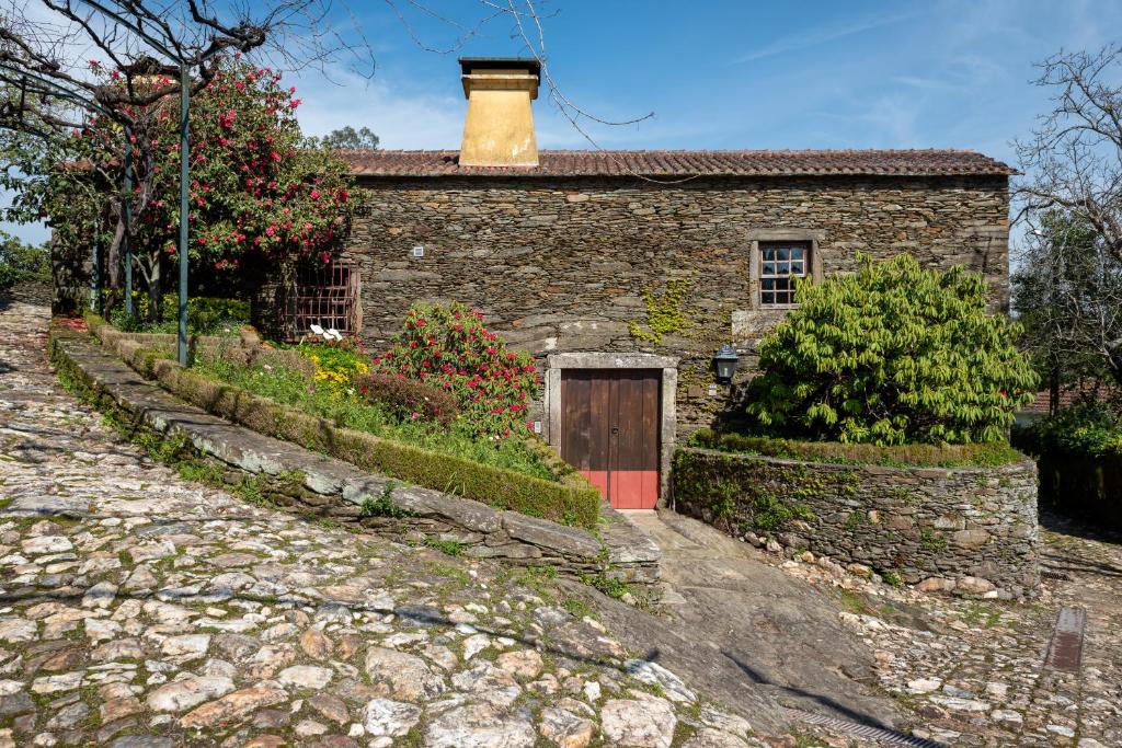 una casa de piedra con una puerta y una chimenea en Quinta de Mourães - Casa do Xisto en Lever