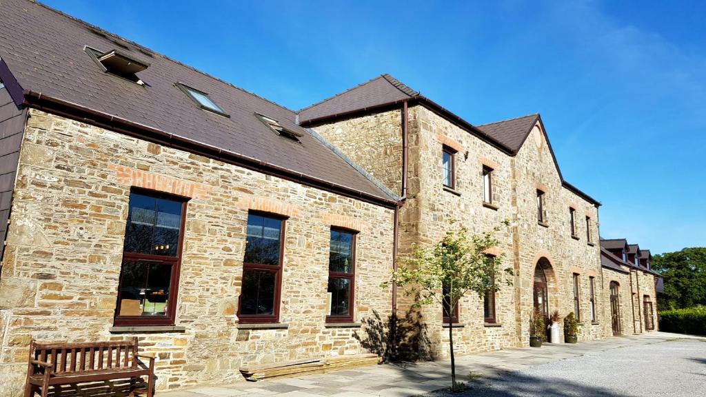 um edifício de tijolos com um banco à frente em LLety Cynin em Llangynin