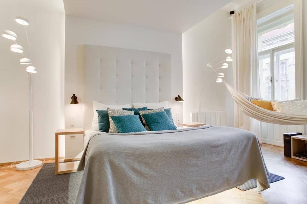 Dormitorio blanco con cama con almohadas azules en BRIGHT Prague Na Poříčí en Praga