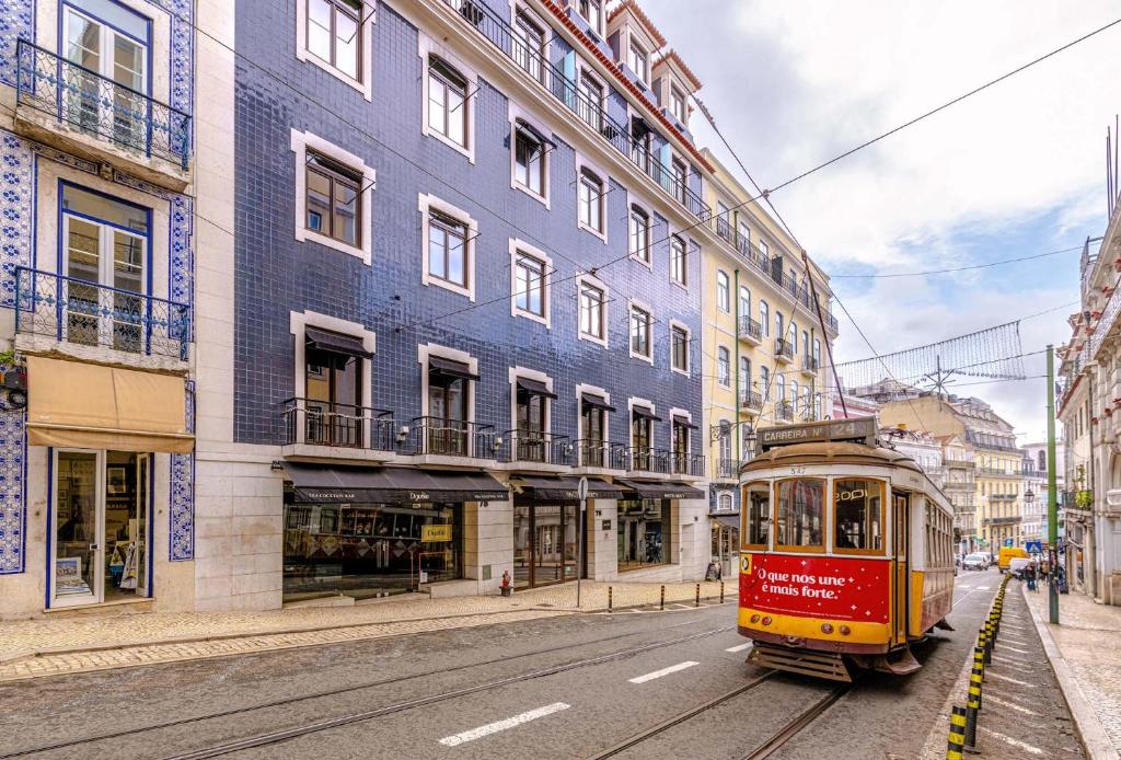 a trolley car on a street in front of a building at 9Hotel Mercy in Lisbon