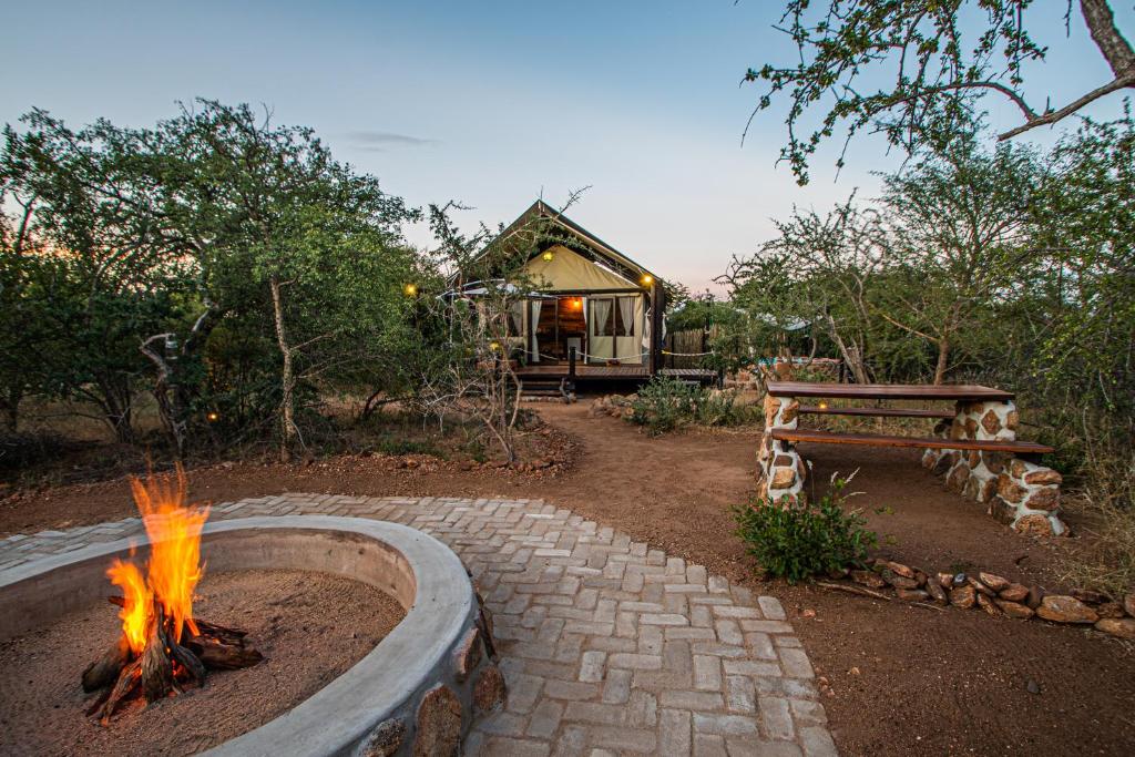 een vuurplaats in een tuin met een huis op de achtergrond bij Mountain View Safari Lodge in Hoedspruit