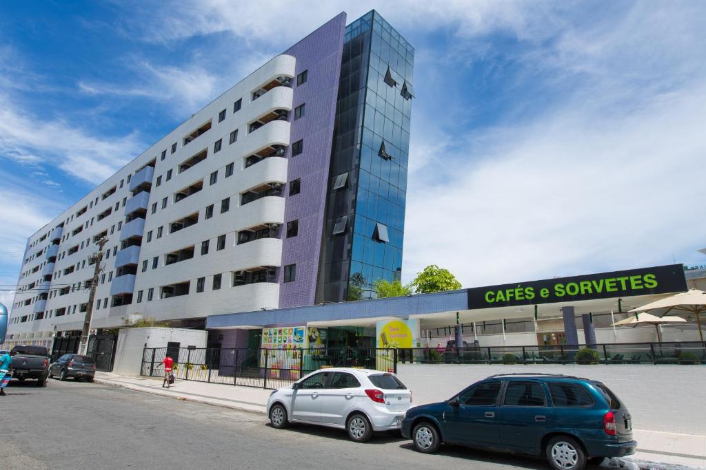 dos coches estacionados frente a un edificio en Flat Beira-Mar - NEO Pajuçara, en Maceió