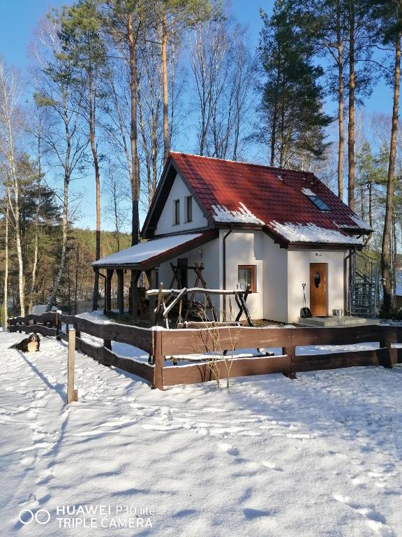 mały biały dom z czerwonym dachem w śniegu w obiekcie Apartament pod Dębem w mieście Bobolice