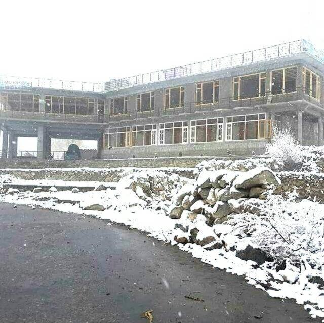 a building in the snow with a bridge in the background at Fairy Land Hotel in Hunza Valley