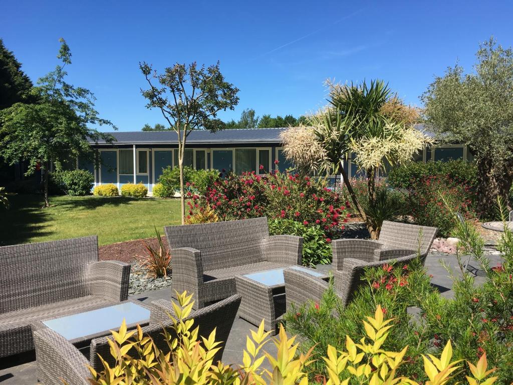 un groupe de chaises et de tables dans un jardin dans l'établissement Hôtel Restaurant Bel Air Crevin - Axe Rennes Nantes, à Crévin