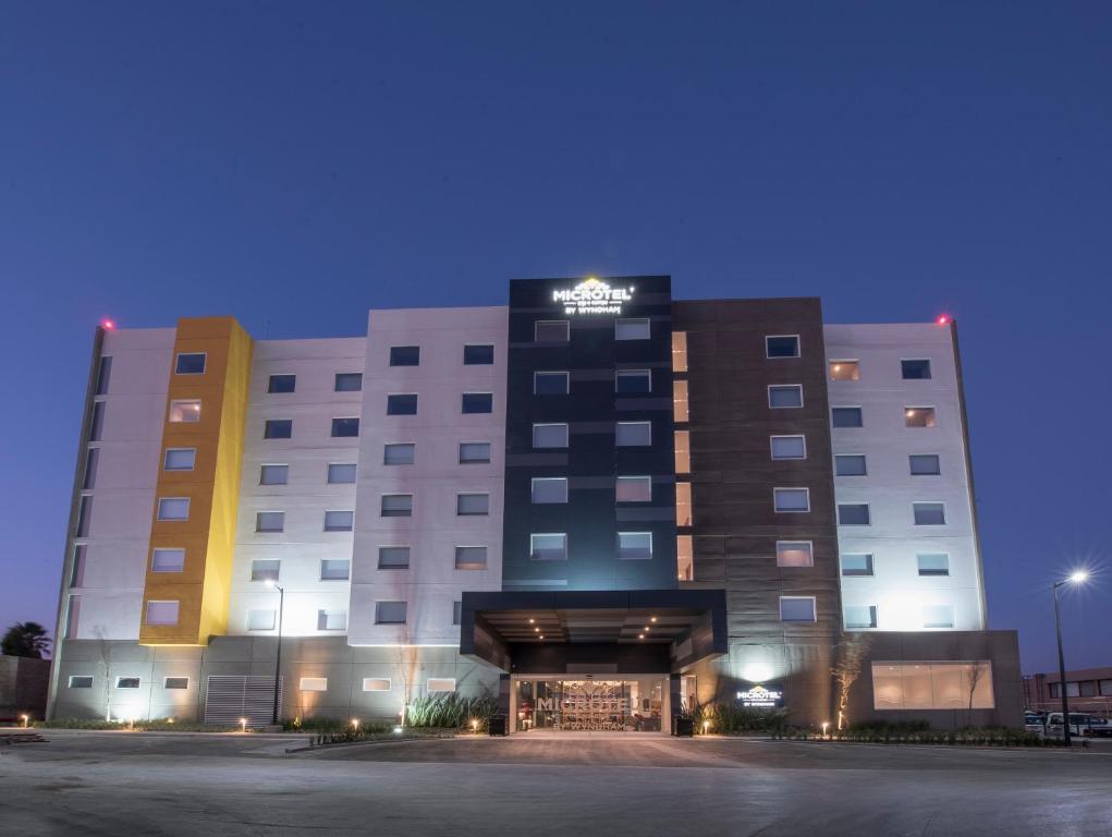 un bâtiment d'hôtel avec un parking la nuit dans l'établissement Microtel Inn & Suites by Wyndham Irapuato, à Irapuato