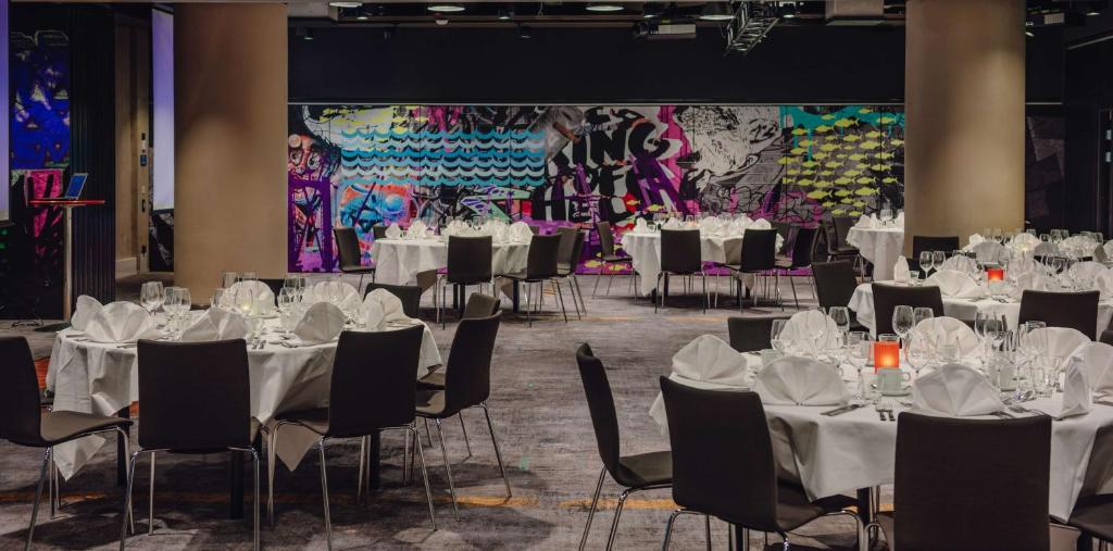 a banquet hall with white tables and chairs and a large screen at Radisson Blu Seaside Hotel, Helsinki in Helsinki
