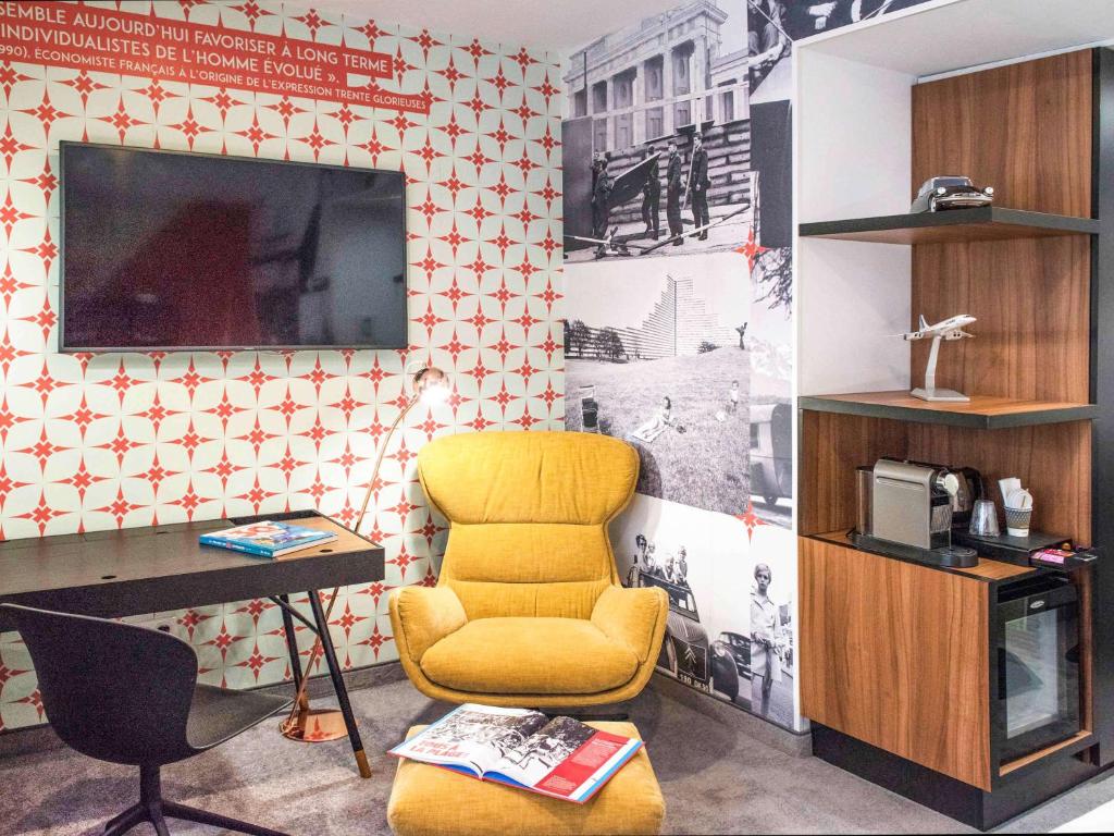 ストラスブールにあるメルキュール ストラスブール サントル プティ フランスの椅子、デスク、テレビが備わる客室です。