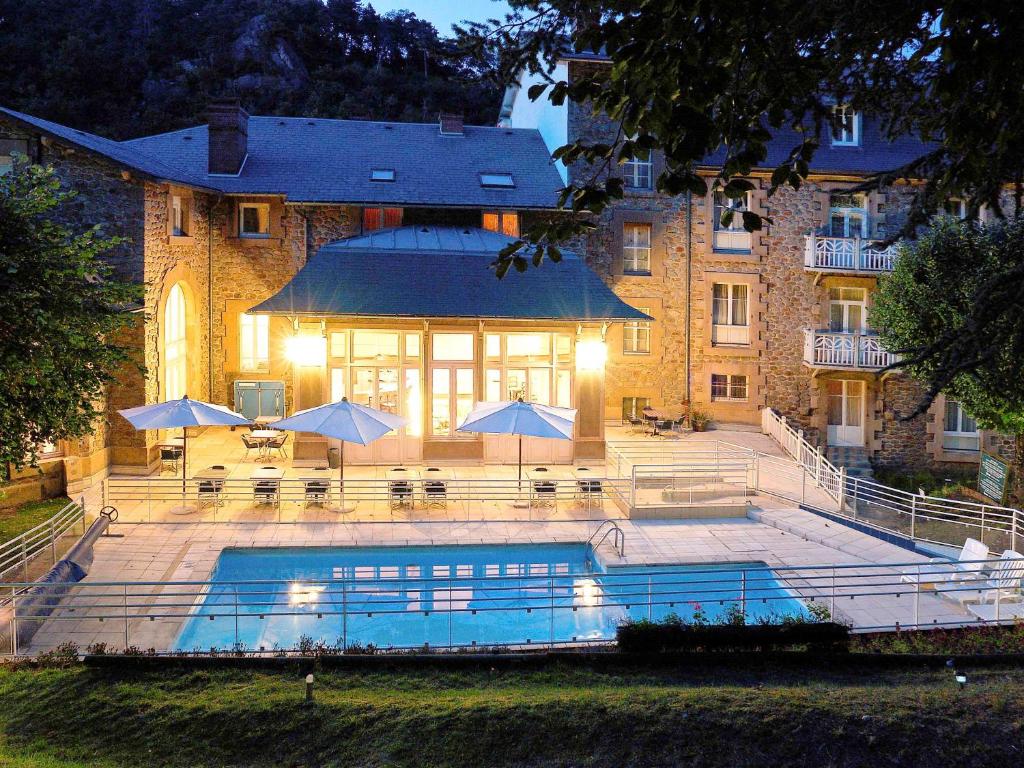 un bâtiment avec une piscine en face d'un bâtiment dans l'établissement Hôtel Mercure Saint-Nectaire Spa & Bien-être, à Saint-Nectaire