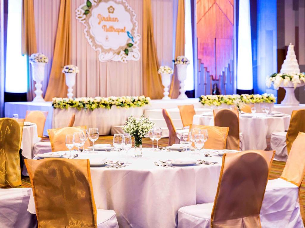 a set of tables in a banquet hall with white table settings at Pullman Khon Kaen Raja Orchid in Khon Kaen
