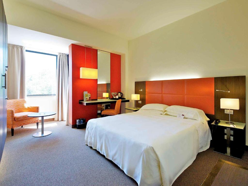 Un dormitorio con una gran cama blanca y una pared roja en Mercure Reggio Emilia Centro Astoria, en Reggio Emilia
