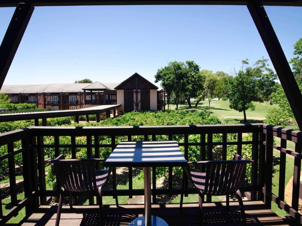 a patio with a table and chairs on a deck at Novotel Vines Resort Swan Valley in Upper Swan