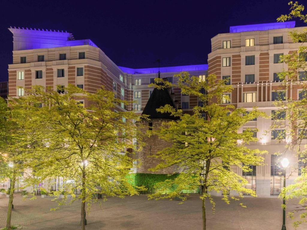 um edifício com árvores à frente à noite em Novotel Brussels City Centre em Bruxelas