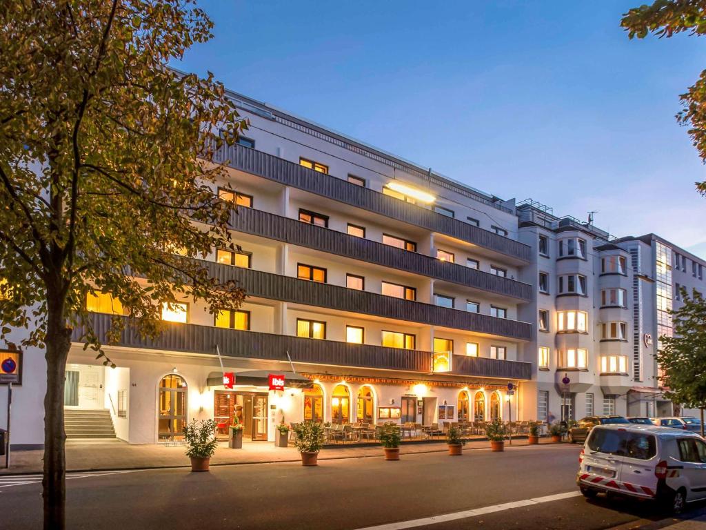 un bâtiment avec une voiture garée devant lui dans l'établissement ibis Saarbrücken City, à Sarrebruck