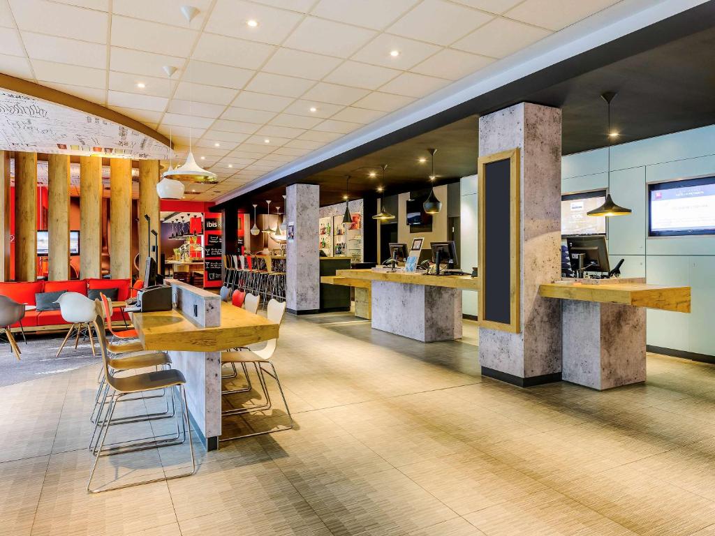 a lobby of a restaurant with tables and chairs at ibis Hotel Frankfurt Airport in Kelsterbach