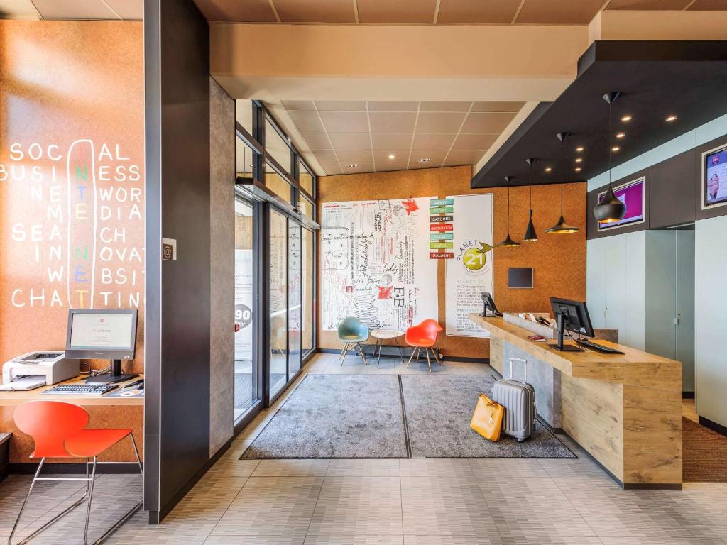 an office with orange chairs and a desk with a computer at ibis Jena City in Jena