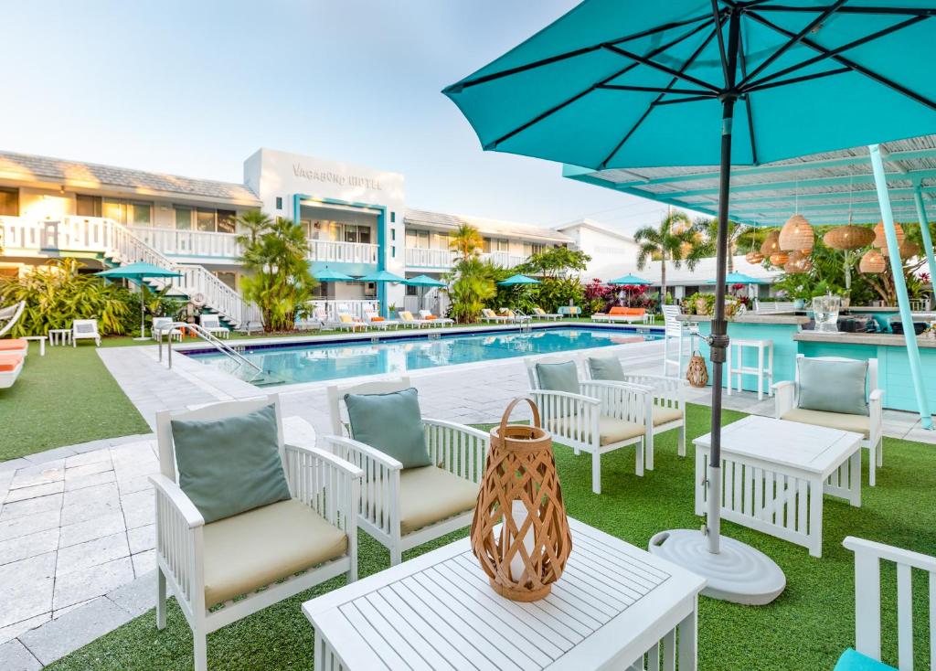 a pool with chairs and tables and an umbrella at The Vagabond Hotel in Miami