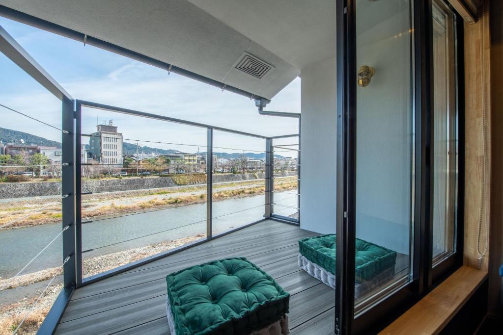 een balkon met groene stoelen en een groot raam bij TABITABI STAY KAWAMA in Kyoto