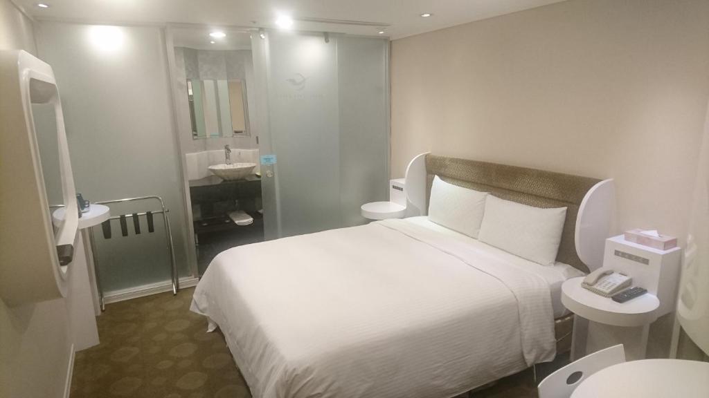 a hotel room with a white bed and a bathroom at Ximen Airline Hotel in Taipei