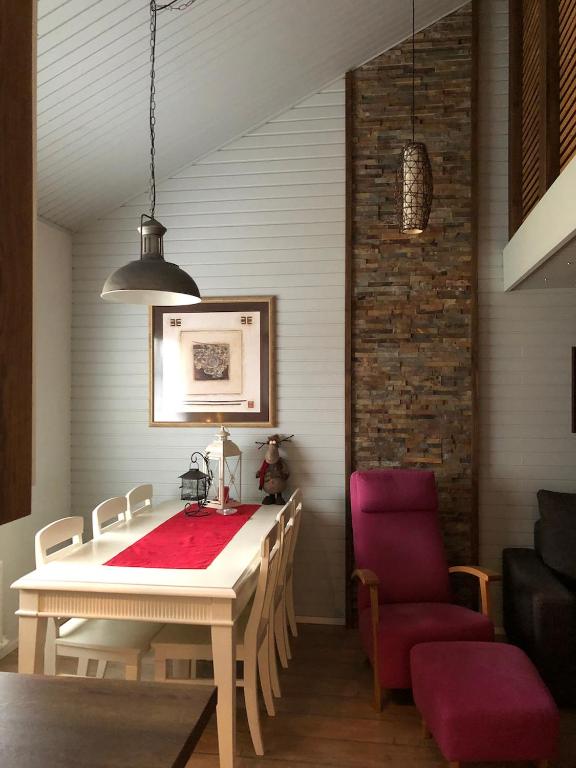 a dining room with a white table and red chairs at Saaritupa Apartment Saariselkä in Saariselka