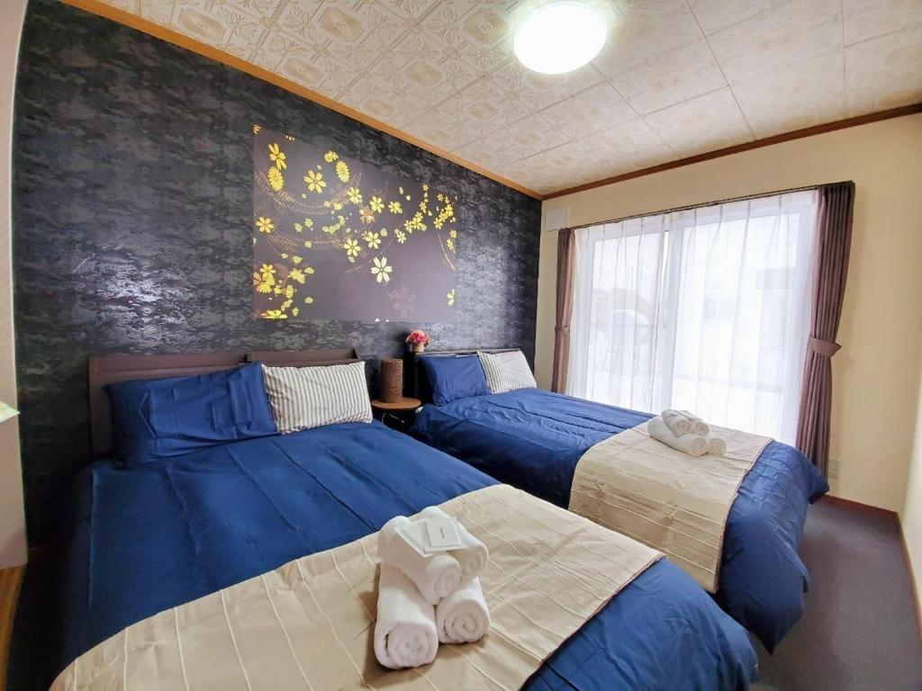 2 Betten in einem Schlafzimmer mit blauer Bettwäsche in der Unterkunft 旭川ファミリーハウスみんみん in Asahikawa