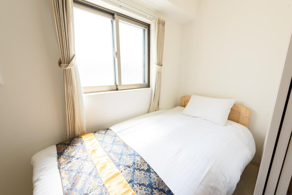 a small bedroom with a white bed and a window at Cocostay KO Residence Sennichimae3Fココステイ ケーオーレジデンス センニチマエ3F in Okayama