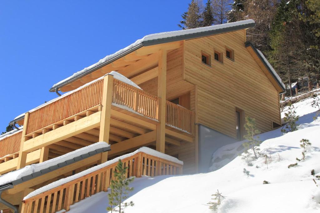 une cabane en rondins dans la neige avec une terrasse dans l'établissement Chalet Sunnseitn - auf der Turracher Höhe, à Turracher Höhe