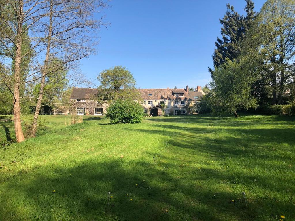 a large field of grass with a house in the background at Moulin de Vilgris in Clairefontaine