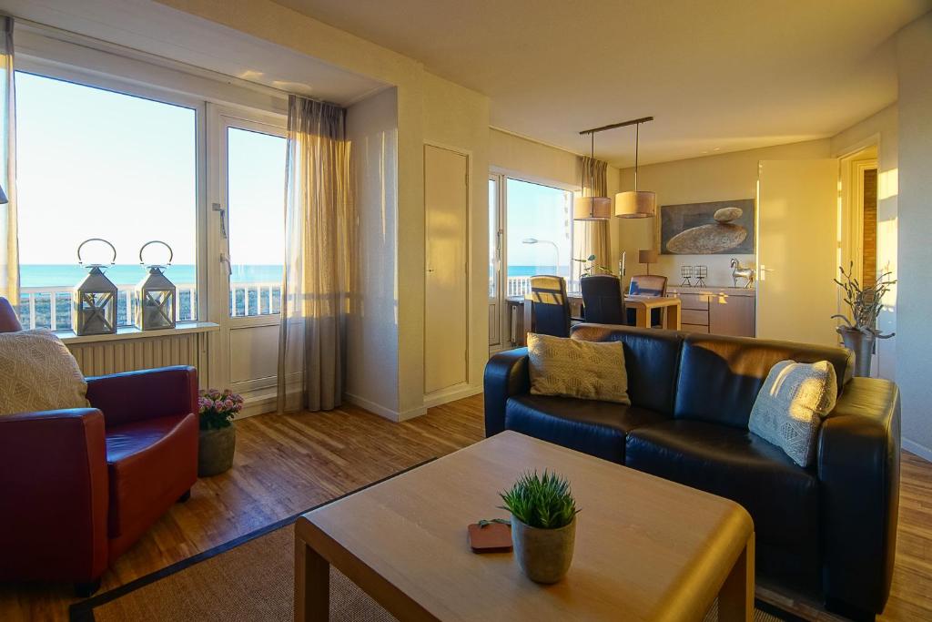 a living room with two couches and a table at Appartementen Zeezicht - 3 in Katwijk aan Zee