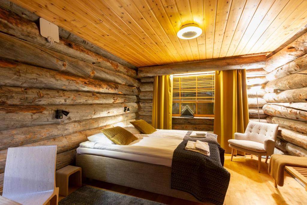 ein Schlafzimmer mit einem Bett und einer Holzwand in der Unterkunft Kuukkeli Log Houses Teerenpesä in Saariselkä