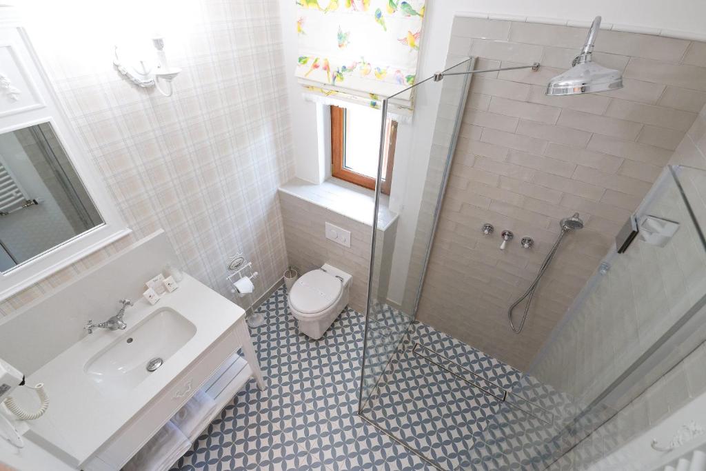 Bright bathroom with patterned floor tiles, glass shower, sink, and window with floral curtain.