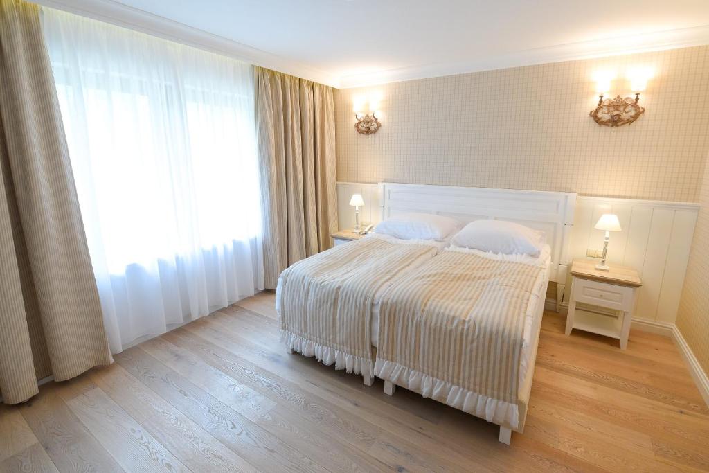 Bright hotel room with twin beds, wooden floor, and soft lighting from wall sconces.