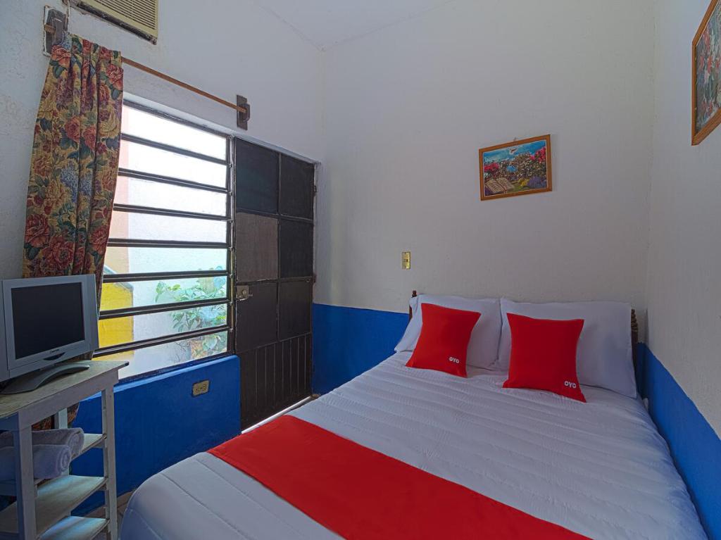 a bedroom with a bed with red pillows and a television at OYO Hotel Posada Los Faroles,Tabasco in Villahermosa